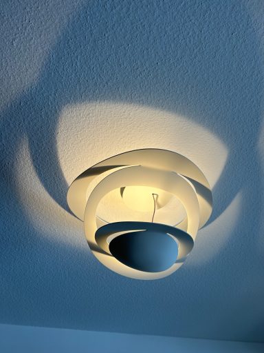 Designerleuchte im Wohnzimmer Deckenlampe mit geschwungenem Design und sanften Schatteneffekten an der Wand.