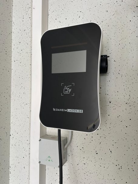 Ladegerät für Elektrofahrzeuge Ladegerät für Elektrofahrzeuge an einer Wand montiert, mit Display und Kabelanschluss.
